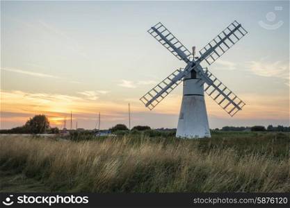 Stunning landscape of windmill and river at sunrise on Summer morning