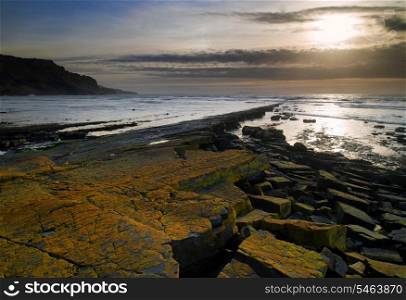 Stunning landscape seascape coastline and rocky shore at sunset