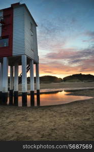 Stunning landscape sunrise stilt lighthouse on beach