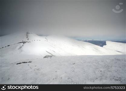 Stunning landscape views from top of deep snow covered mountains in Winter in cloud inversion