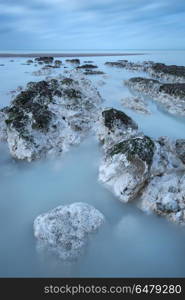 Stunning long exposure landscape image of low tide beach with ro. Beautiful long exposure landscape image of low tide beach with rocks at sunrise