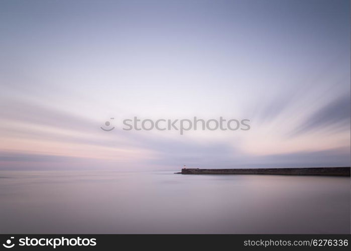 Stunning long exposure landscape lighthouse at sunset with calm sea