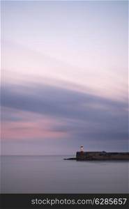 Stunning long exposure landscape lighthouse at sunset with calm sea
