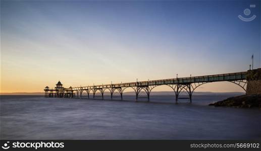 Stunning long exposure sunset over ocean with pier silhouette