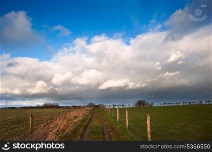 Stunning moody sky with beautiful cloud formations and colors over countryside landscape of path leading into distance