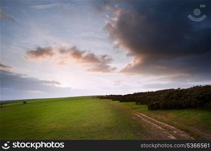 Stunning moody sky with beautiful cloud formations and colors over countryside landscape of path leading into distance