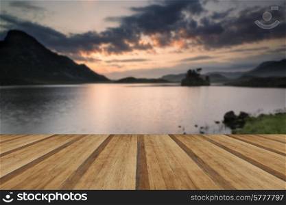 Stunning mountain and lake sunrise reflections beautiful landscape. Beautiful sunrise reflected in calm Lakes landscape with wooden planks floor