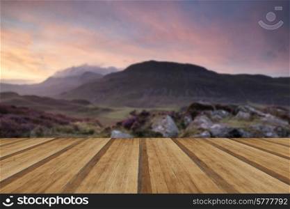 Stunning Summer sunrise over mountain range with lake and beautiful sky with wooden planks floor