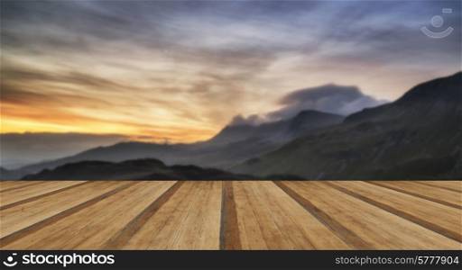 Stunning Summer sunrise over mountain range with lake and beautiful sky with wooden planks floor