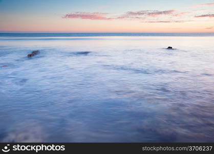 Stunning Summerr sunset over ocean with rocks and vibrant colors