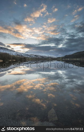 Stunning sunrise landscape image in Winter of Llyn Cwellyn in Sn. Beautiful sunrise landscape image in Winter of Llyn Cwellyn in Snowdonia National Park with snow capped mountains in background