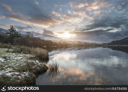Stunning sunrise landscape image in Winter of Llyn Cwellyn in Sn. Beautiful sunrise landscape image in Winter of Llyn Cwellyn in Snowdonia National Park with snow capped mountains in background