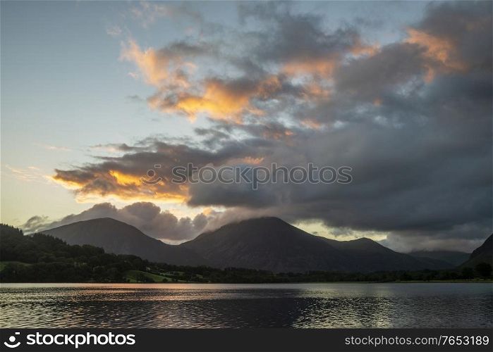 Stunning sunrise landscape image looking across Loweswater in the Lake District towards Low Fell and Grasmere with colorful sky breaking on the mountain peaks