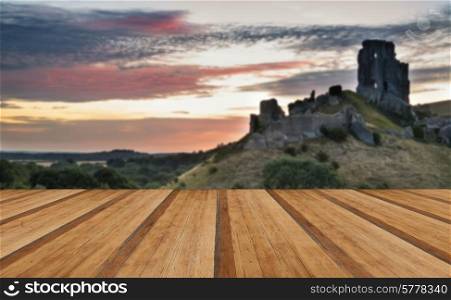 Stunning sunrise landscape over ruins of medieval castle with wooden planks floor