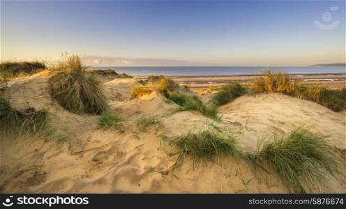 Stunning sunrise over sand dunes system on yellow sand golden beach