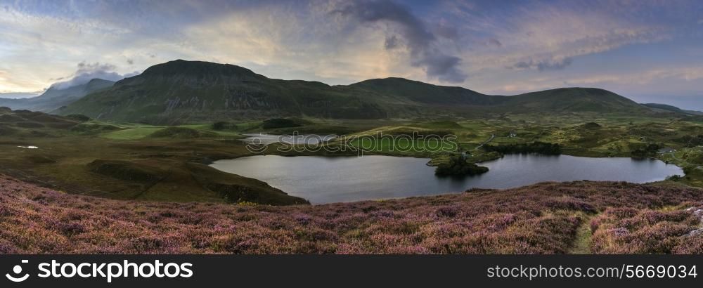 Stunning sunrise panorama landscape of heather with mountain lake and mountain range