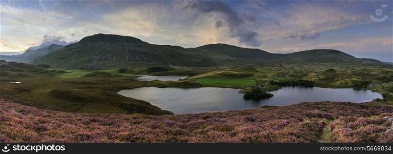 Stunning sunrise panorama landscape of heather with mountain lake and mountain range