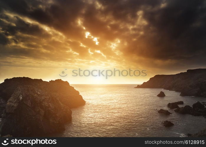 Stunning sunset landscape over rocky cove looking out to sea