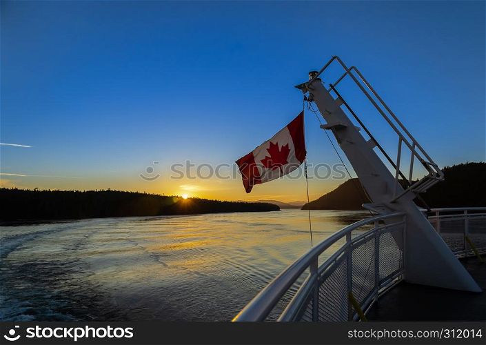 Stunning sunset view with Canadian flag weaving on the deck of ferry to Victoria in British Columbia, Canada