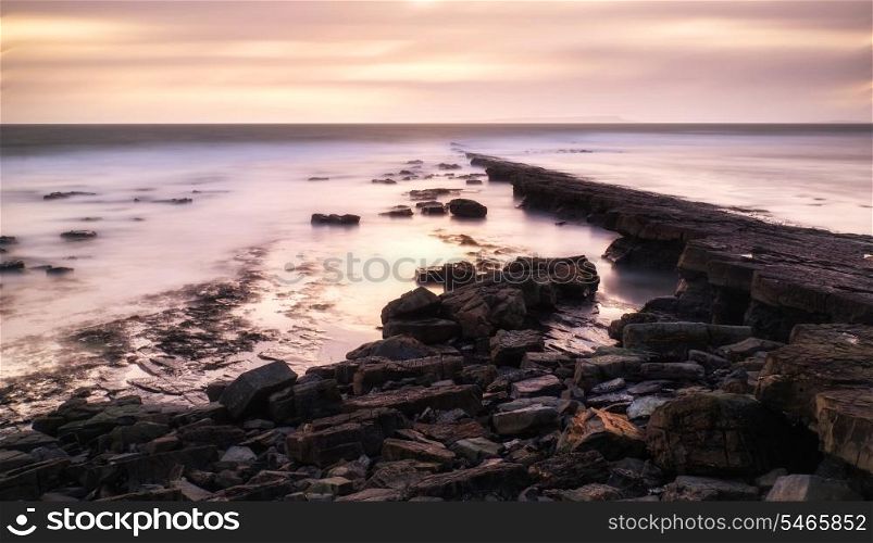 Stunning toned landscape seascape coastline and rocky shore at sunset