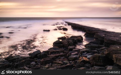 Stunning toned landscape seascape coastline and rocky shore at sunset