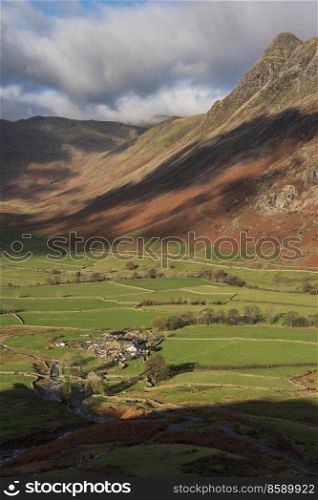 Stunning vibrant Autumn landscape image looking from Pike O’Blisco towards Langdale Pikes and Range with beautiful sungiht on mountains and valley