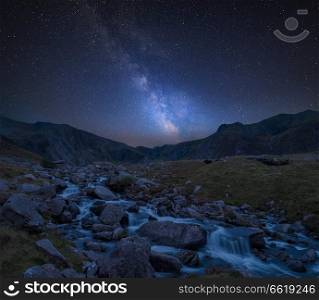 Stunning vibrant Milky Way composite image over Landscape image of river flowing down mountain range near Llyn Ogwen and Llyn Idwal in Snowdonia