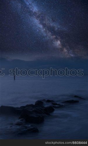 Stunning vibrant Milky Way composite image over landscape of rocks in sea