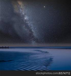 Stunning vibrant Milky Way composite image over landscape of view along beach at low tide