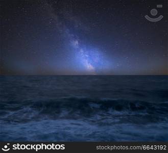 Stunning vibrant Milky Way composite image over landscape of Waves breaking onto beach