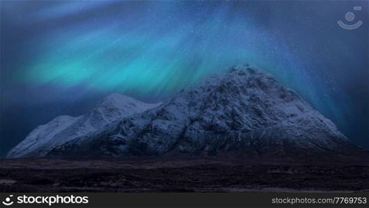 Stunning vibrant Northern Lights Aurora composite image over landscape of snowcapped mountains in Scottish Highlands