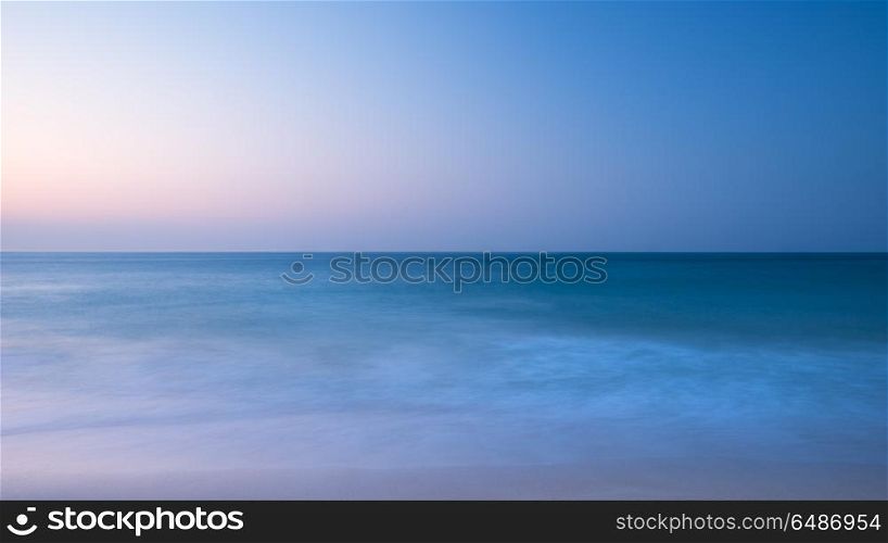 Stunning vibrantl sunrise landscape image of calm sea looking ou. Beautiful colorful sunrise landscape image of calm sea looking out from Porthcurno beach on South Cornwall coast in England