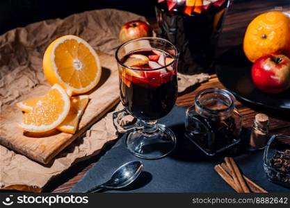 Stunning view of hot mulled wine with honey, fruits and spices. Fragrant atmosphere of Christmas winter holiday. Glass with cinnamon and orange on table.High quality. Stunning view of hot mulled wine with honey, fruits and spices.