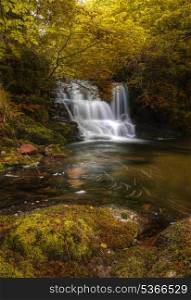 Stunning waterfall in beautiful Autumn Fall colors dense forest landscape