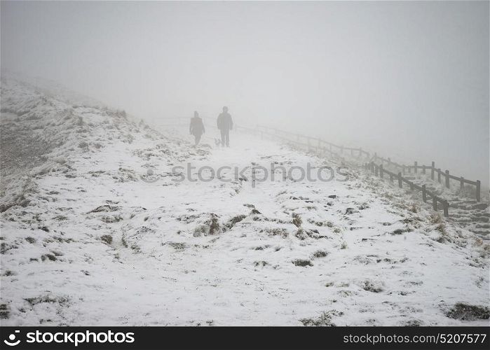 Stunning Winter landscape image around Mam Tor countryside in Peak District England with hikers in fog