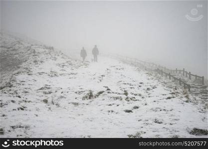 Stunning Winter landscape image around Mam Tor countryside in Peak District England with hikers in fog