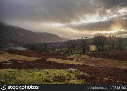 Stunning Winter sunset golden hour landscape image of view from Wast Water over countryside in Lake District towards the Western district