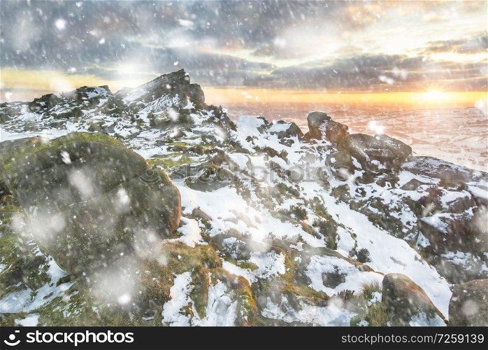 Stunning Winter sunset landscape from mountains looking over countryside in heavy snow storm