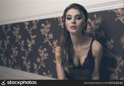 stunning woman with long brown hair and cute make-up posing with elegant lace lingerie and looking in camera with charming expression