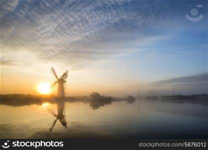 Stunnnig landscape of windmill and river at sunrise on Summer morning