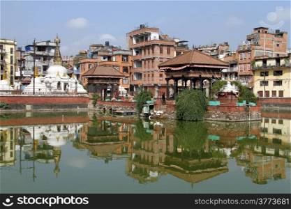 Stupa and buildings near pond with green water