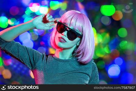 style, fashion and nightlife concept - happy young woman in pink wig and black sunglasses over night lights background. happy woman in pink wig and black sunglasses