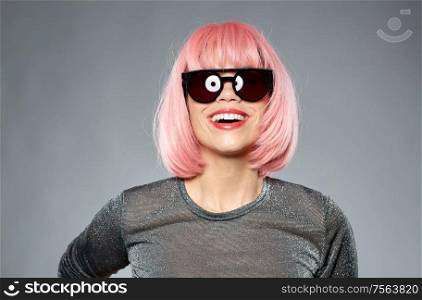 style, fashion and people concept - happy young woman in pink wig and black sunglasses over grey background. happy woman in pink wig and black sunglasses