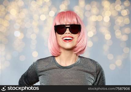 style, fashion and people concept - happy young woman in pink wig and black sunglasses over festive lights background. happy woman in pink wig and black sunglasses