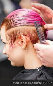 Styling female hair. Male hairdresser makes hairstyle for a young woman in a beauty salon. Styling female hair. Male hairdresser makes hairstyle for a young woman in a beauty salon.