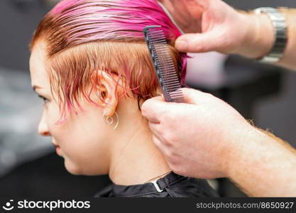 Styling female hair. Male hairdresser makes hairstyle for a young woman in a beauty salon. Styling female hair. Male hairdresser makes hairstyle for a young woman in a beauty salon.
