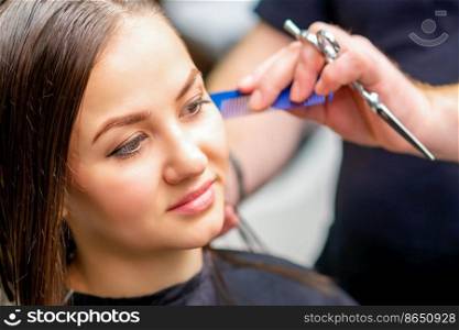 Styling female hair. Male hairdresser makes hairstyle for a young woman in a beauty salon. Styling female hair. Male hairdresser makes hairstyle for a young woman in a beauty salon.