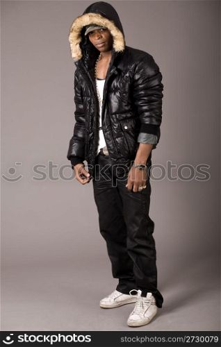 Stylish acrobat young african with black jacket and head cap on grey background