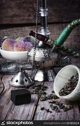 Stylish Arabic hookah. Arab hookah metal and scattered tobacco leaf