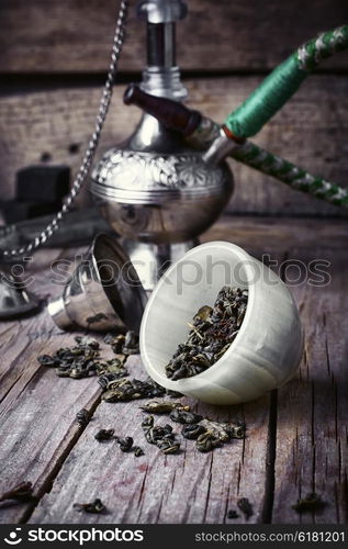 Stylish Arabic hookah. Arab hookah metal and scattered tobacco leaf